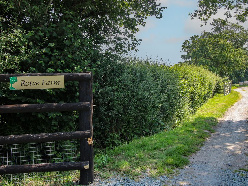 A sign for Rowe Farm next to a gravel path surrounded by hedges near Broadstone near Munslow