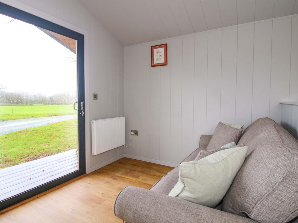 A snug area with a sofa and a window at Leafy Oak Lodge in Munslow