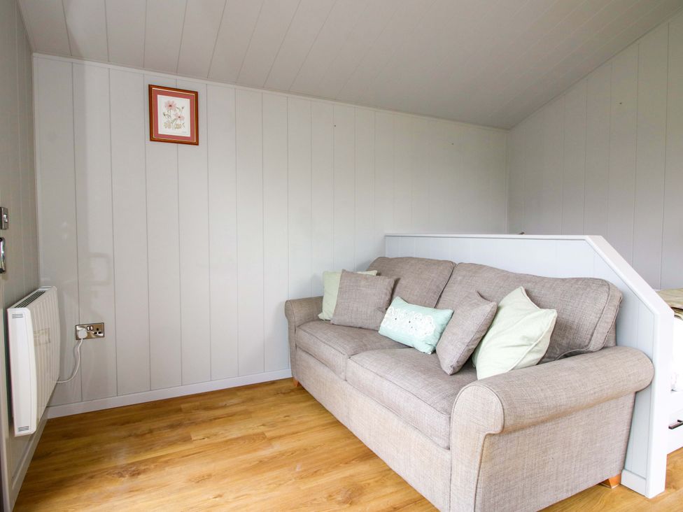 A living room with a sofa and cushions at Leafy Oak Lodge in Munslow