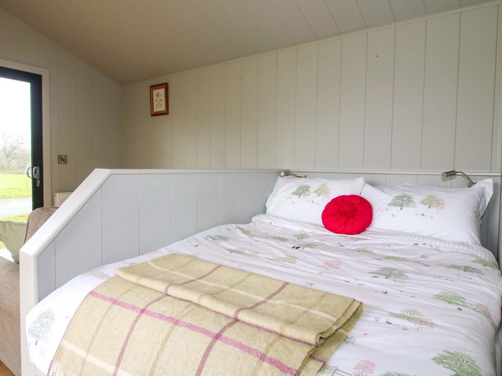 A bedroom with a bed and a window at Leafy Oak Lodge in Munslow