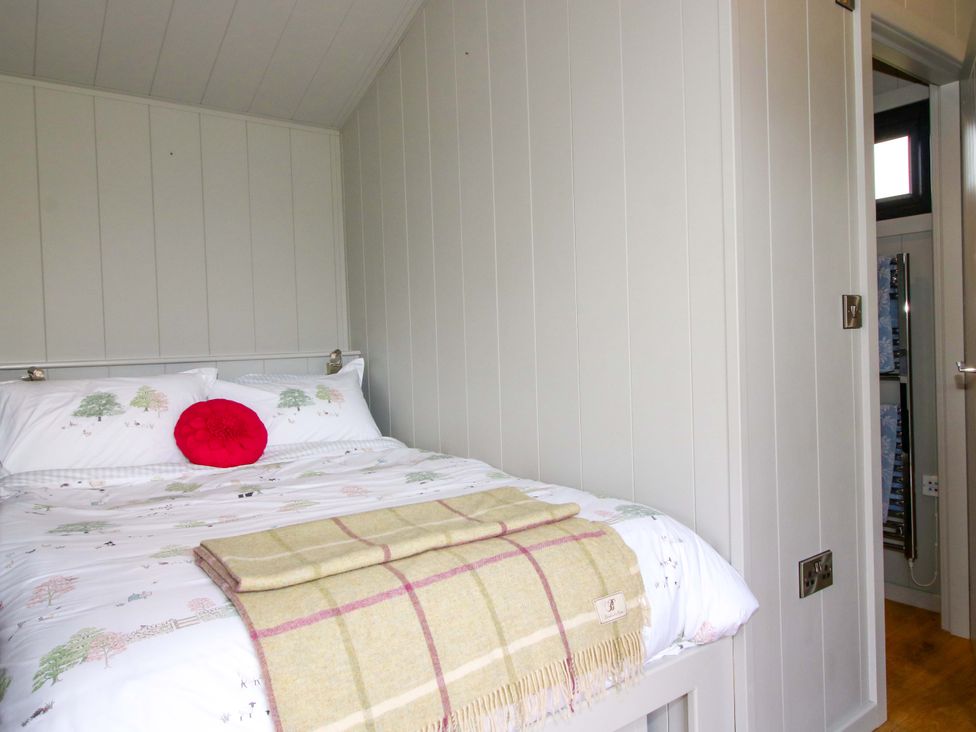 A bedroom with a bed and throw blanket at Leafy Oak Lodge in Munslow