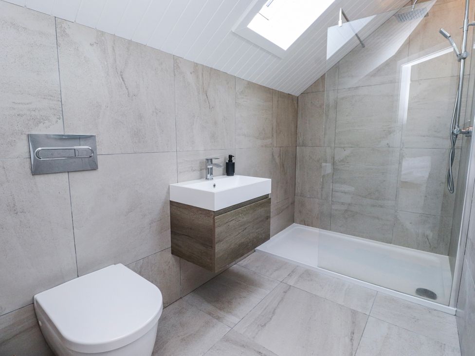 A bathroom with a toilet, vanity, and shower at Bigting in Rhosneigr