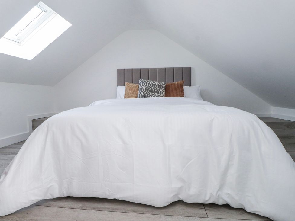 A bedroom with a bed and cushions at Bigting in Rhosneigr