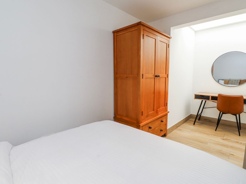 A bedroom with a bed, wardrobe, desk, and chair at Bigting in Rhosneigr