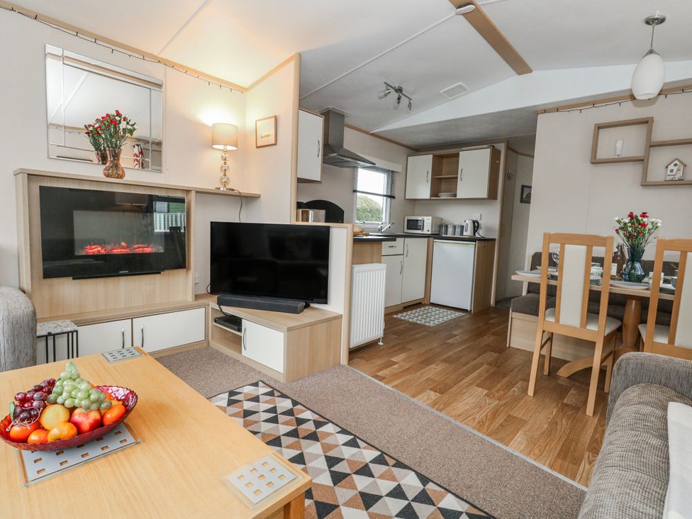 A living room with a sofa and dining area at Swanage Coastal Park Caravan Swanage