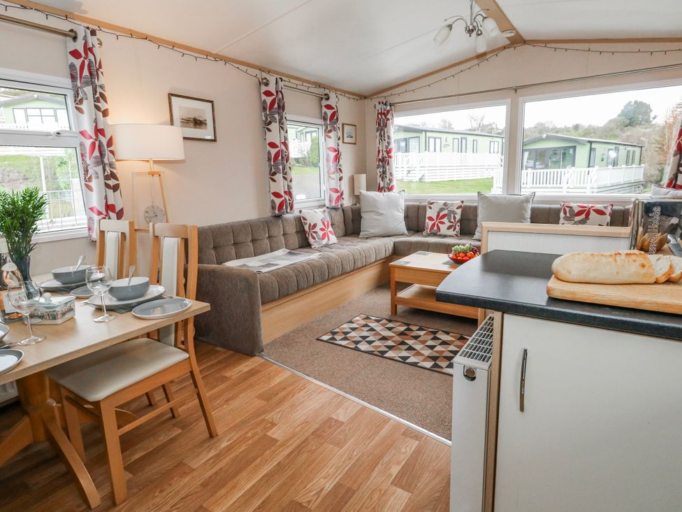 A living room with a sofa and dining area at Swanage Coastal Park Caravan in Swanage