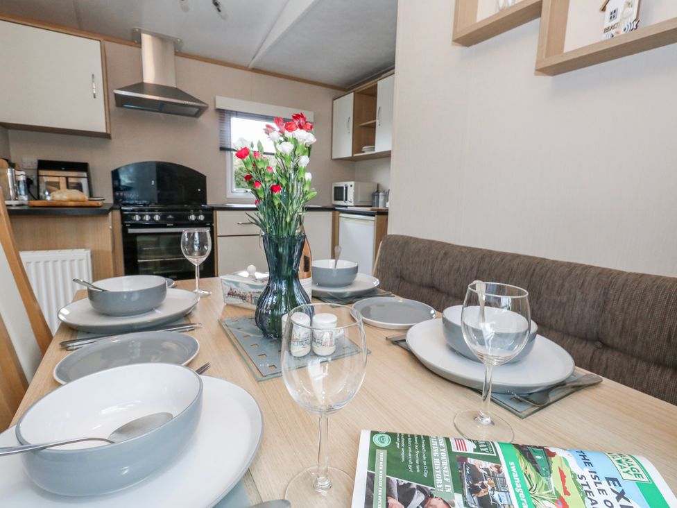 A dining table set with plates and glasses at Swanage Coastal Park Caravan in Swanage