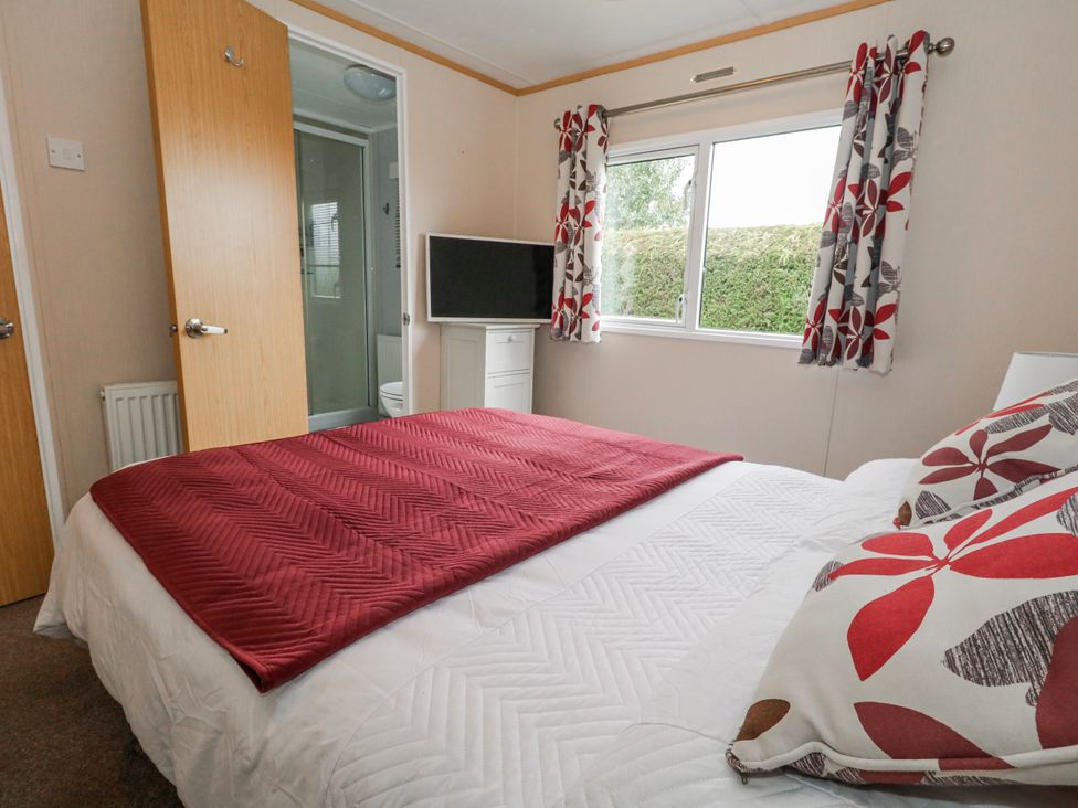 A bedroom with a bed and television at Swanage Coastal Park Caravan in Swanage