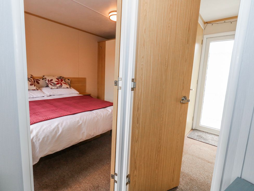 A bedroom with a bed and cabinet at Swanage Coastal Park Caravan in Swanage