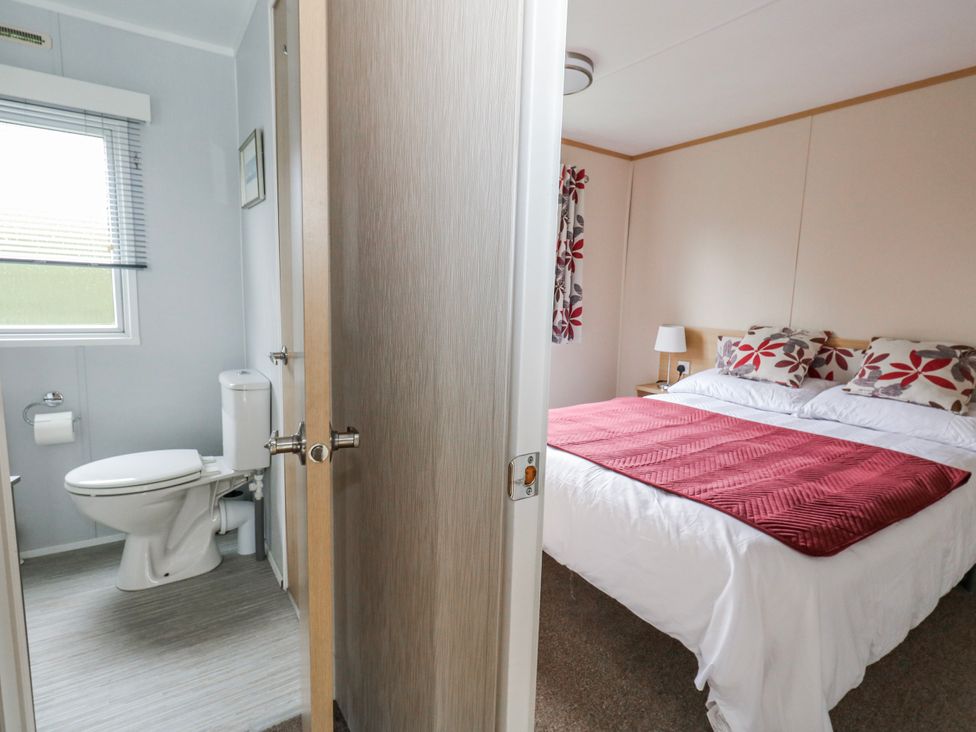 A bedroom with a bed and connecting bathroom at Swanage Coastal Park Caravan in Swanage