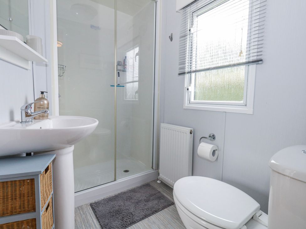 A bathroom with a shower, toilet, and sink at Swanage Coastal Park Caravan in Swanage
