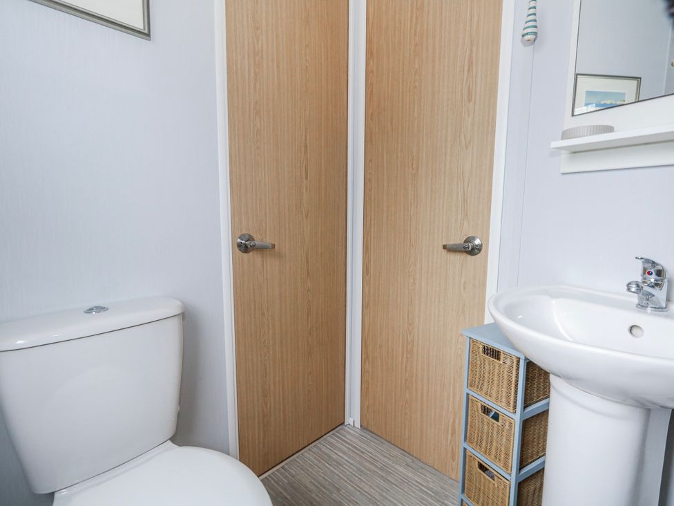 A bathroom with a toilet and sink in Swanage Coastal Park Caravan in Swanage