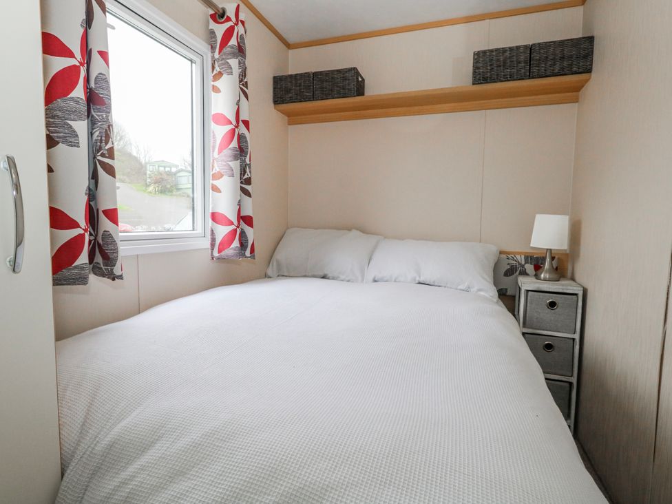 A bedroom with a bed and pillows at Swanage Coastal Park Caravan in Swanage