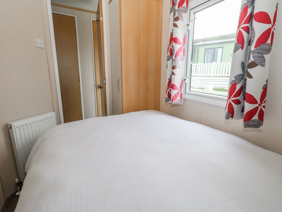 A bedroom with a bed and window at Swanage Coastal Park Caravan in Swanage