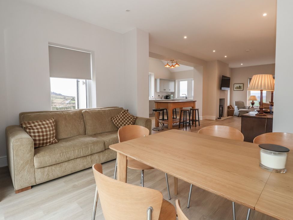 A living room with a sofa and dining area at Daisy Mount in Keighley