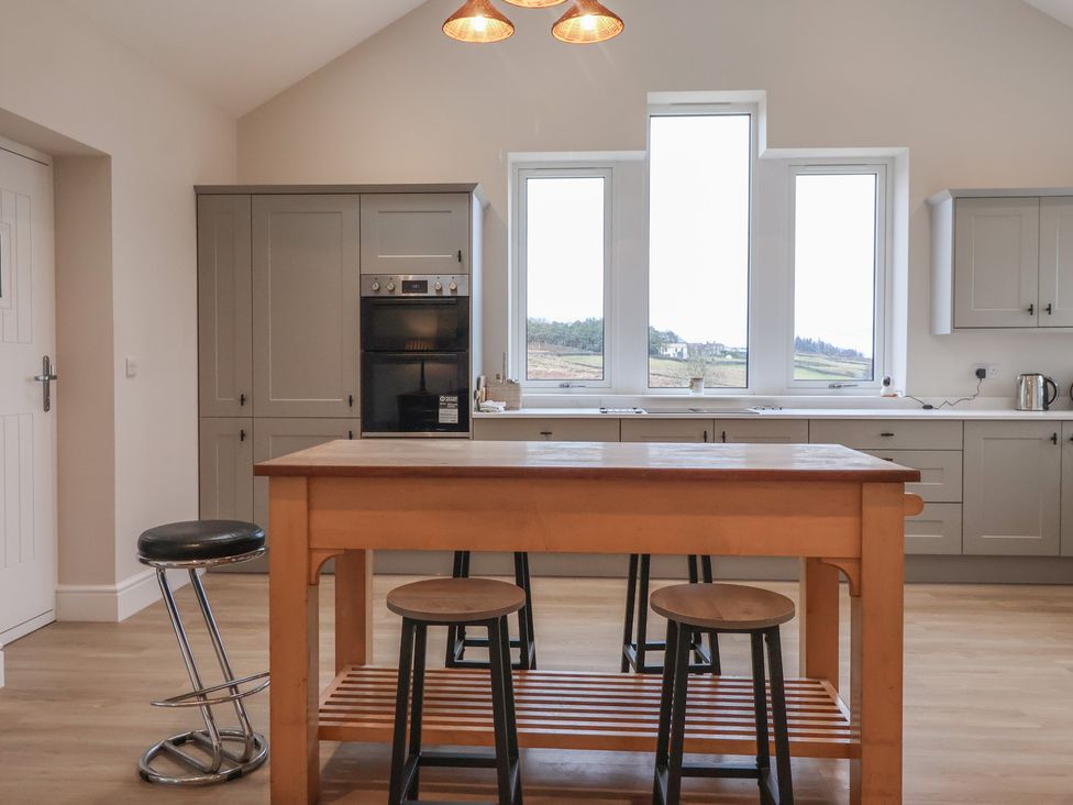 A kitchen with an island and stools at Daisy Mount in Keighley