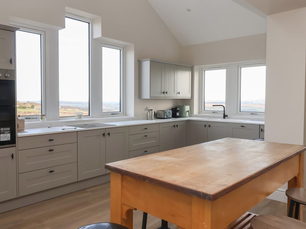 A kitchen with cabinets and a table at Daisy Mount in Keighley