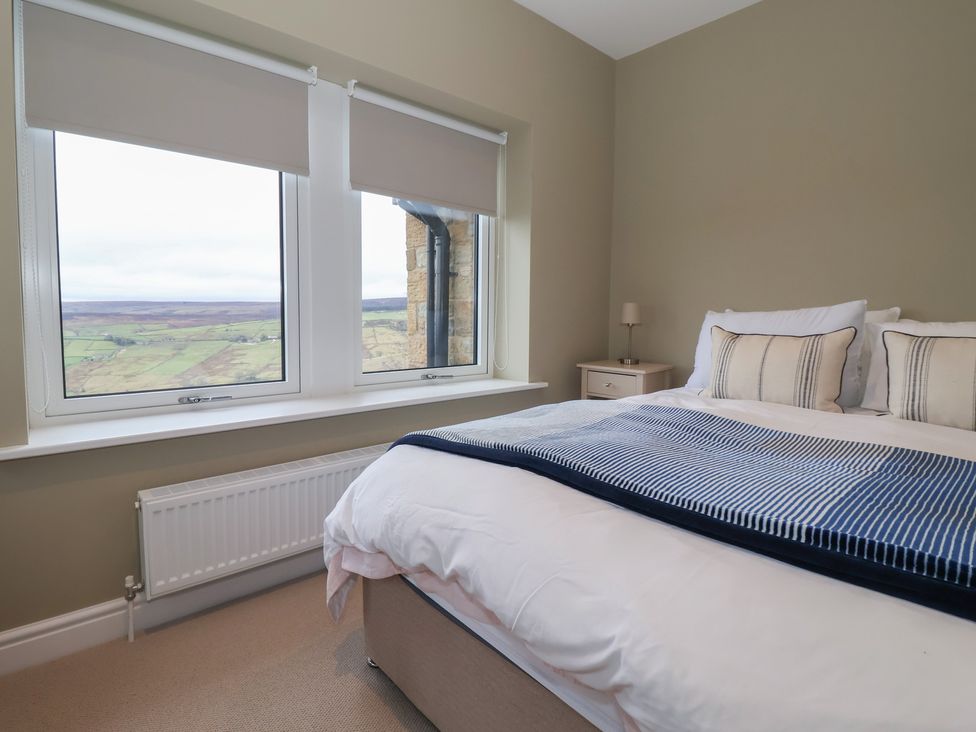 A bedroom with a bed and windows showing a landscape view at Daisy Mount in Keighley