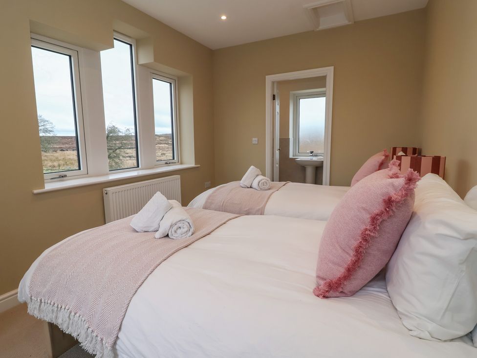 A bedroom with two beds and a view outside at Daisy Mount in Keighley