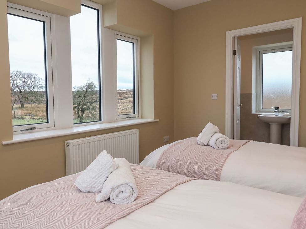 A bedroom with two beds and an en-suite bathroom at Daisy Mount in Keighley