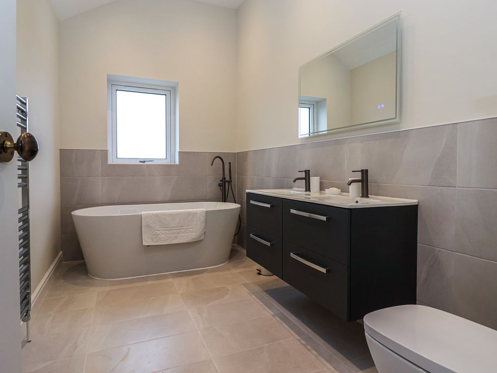 A bathroom with a bathtub, sink, and toilet at Daisy Mount in Keighley