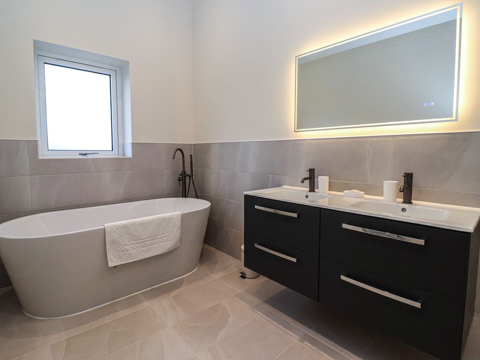 A bathroom with a bathtub, sink and mirror at Daisy Mount, Keighley