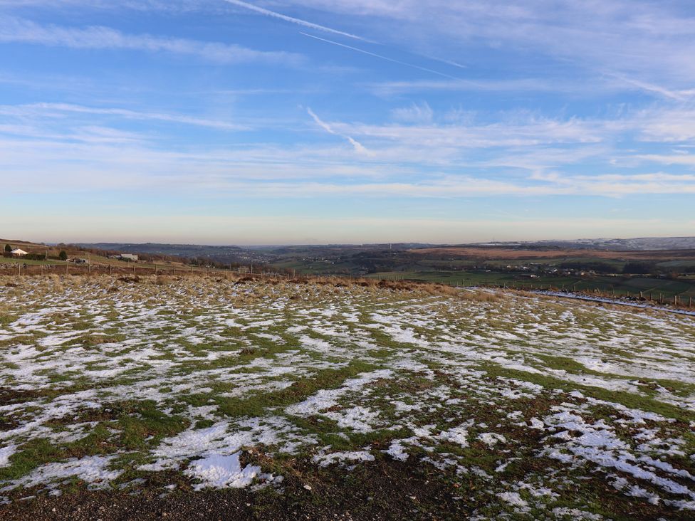 A snowy landscape with green grass and a blue sky at Daisy Mount in Keighley