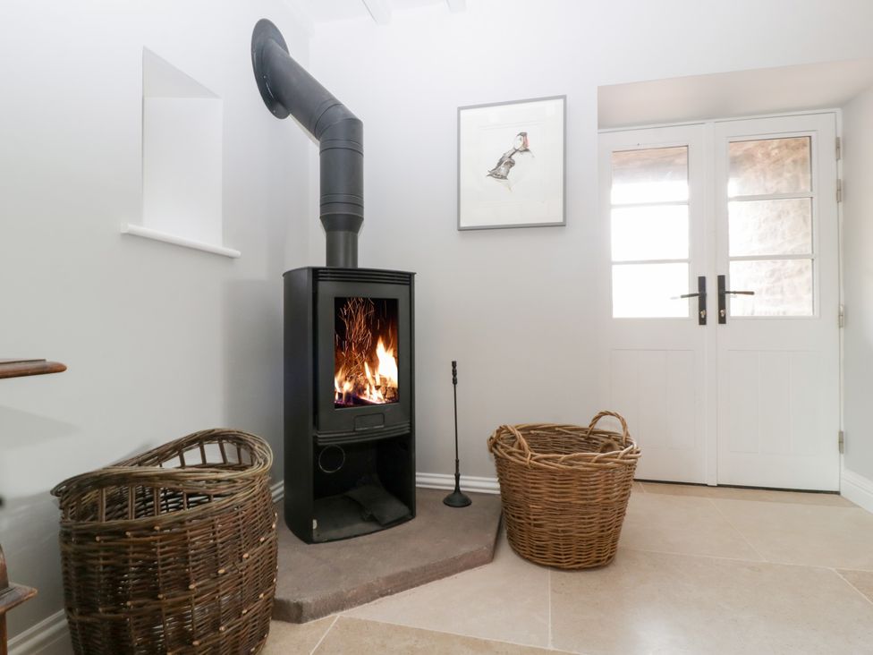 A living room with a wood burning stove and baskets at Velindra Farm Cottage Hereford