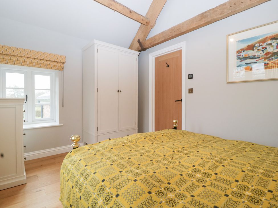 A bedroom featuring a bed, wardrobe, and window at Velindra Farm Cottage Hereford