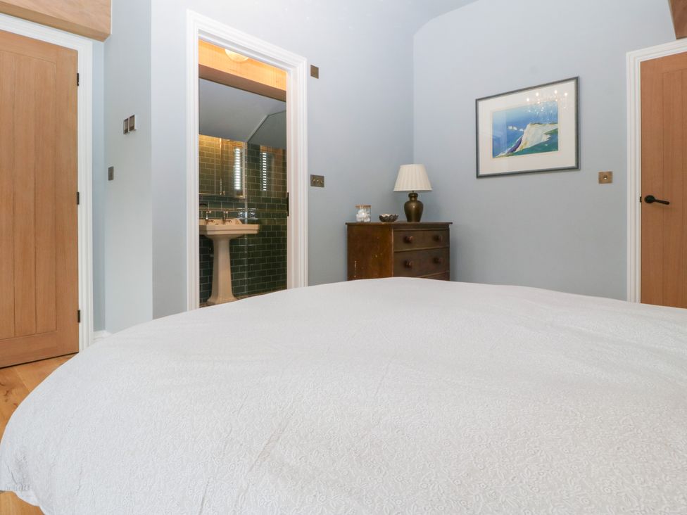 A bedroom with furniture and a bathroom entrance at Velindra Farm Cottage Hereford