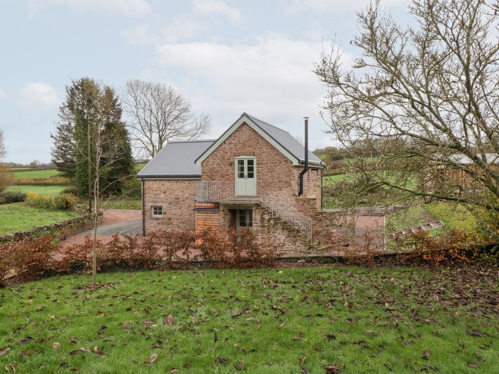 A house with a stone exterior and stairs leading to the door at Velindra Farm Cottage in Hereford