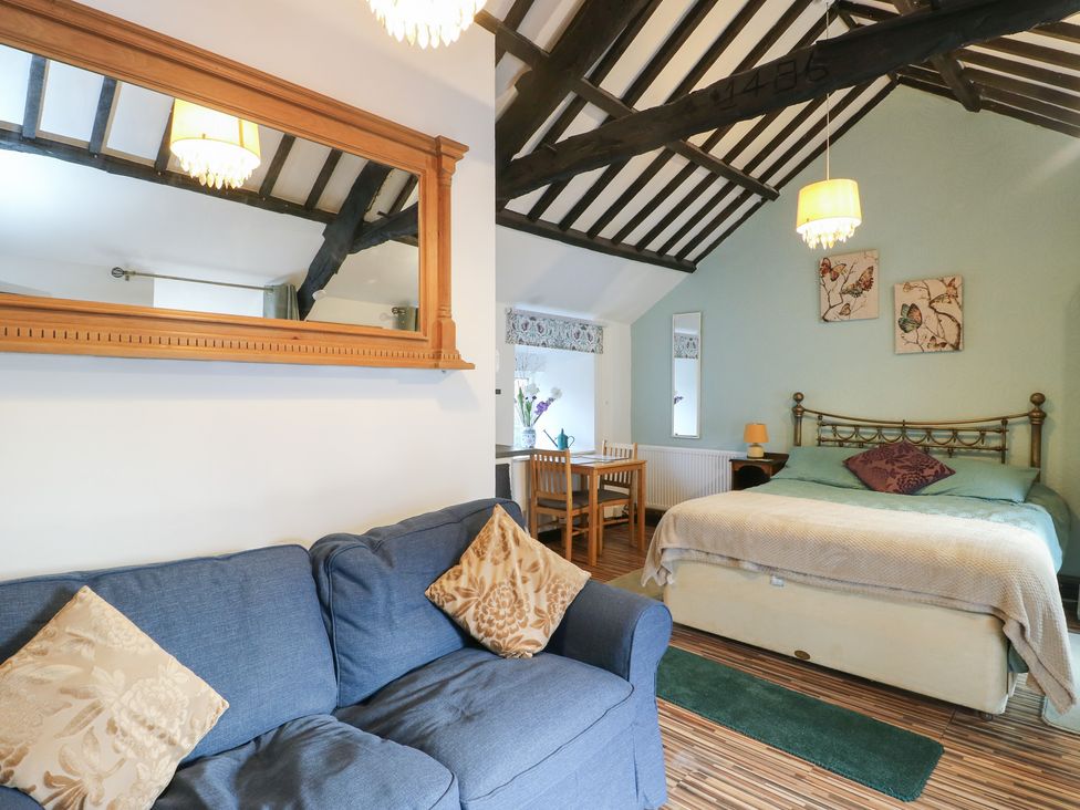 A bedroom with a bed, sofa and dining table at Fullers Studio, Caergeiliog
