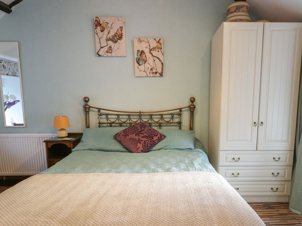 A bedroom with a bed and wardrobe at Fullers Studio in Caergeiliog