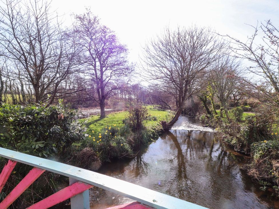 A stream with trees and grass at The Mill in Caergeiliog