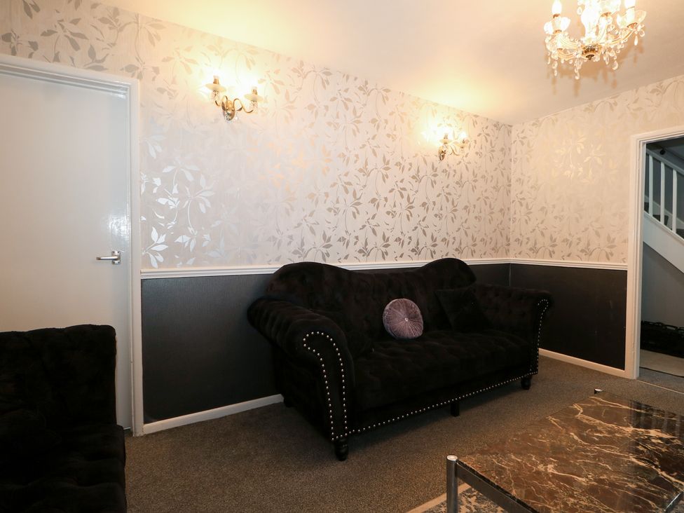 A living room featuring a black sofa and chandelier at 24 Dunkirk Close Romney Marsh