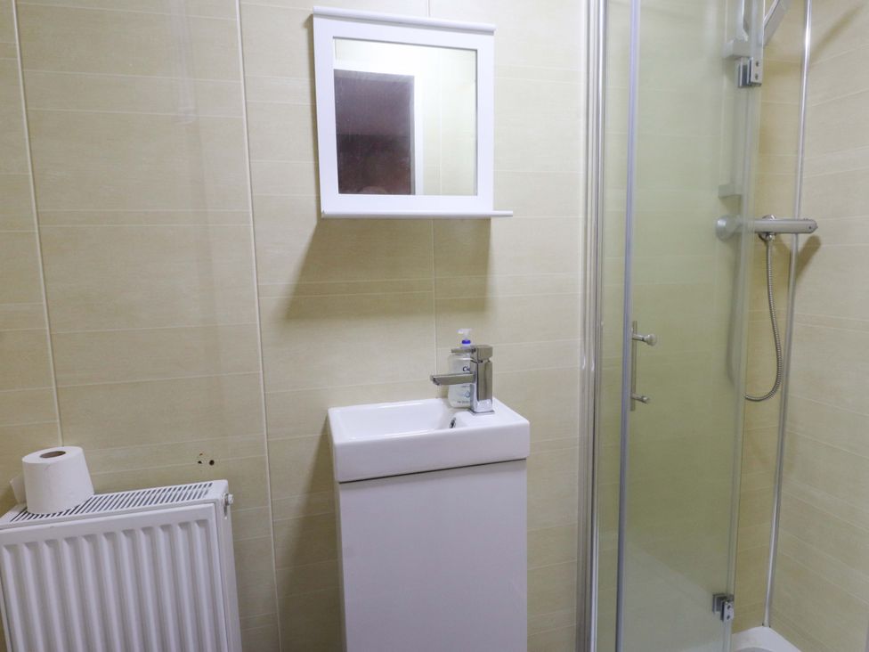 A bathroom with a sink shower and mirror at Ty Crigyll in Holyhead