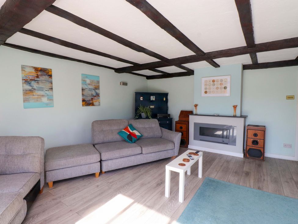 A living room with a sofa, coffee table, and fireplace at Ty Crigyll in Caergeiliog