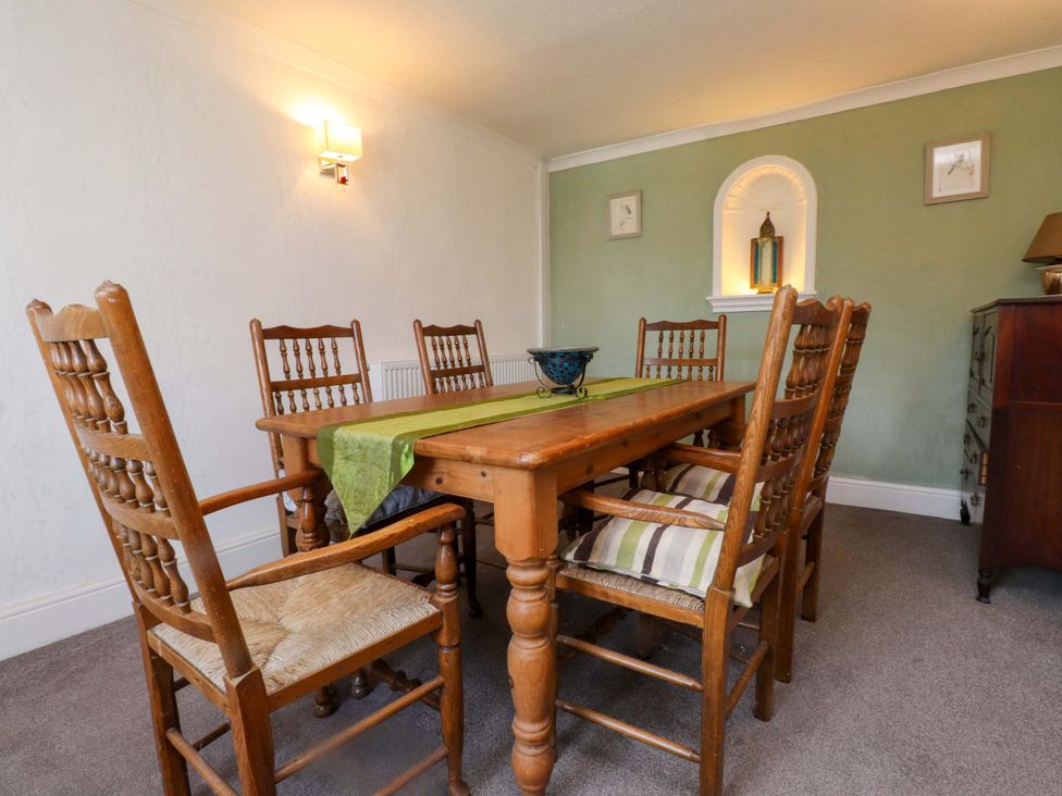 A dining room with a wooden table and chairs at Ty Crigyll in Caergeiliog