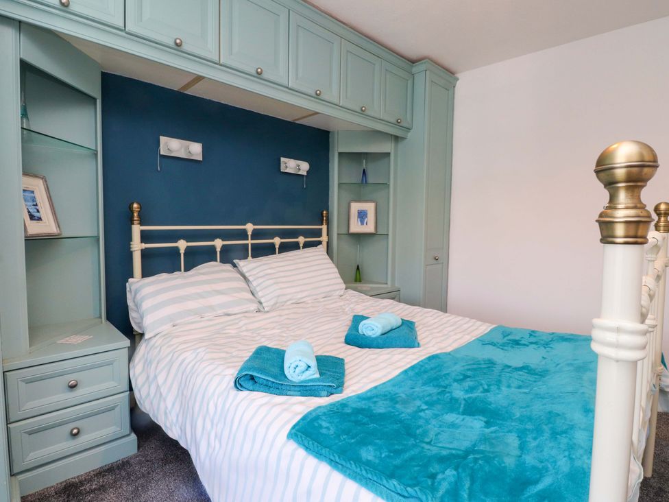 A bedroom with a bed and shelves at Ty Crigyll in Caergeiliog