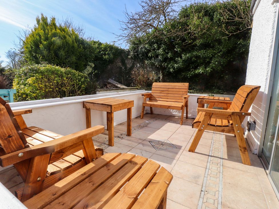 A wooden patio with chairs and a table at Ty Crigyll in Caergeiliog