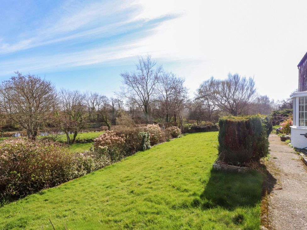 A garden with grass, trees, and a pathway at Ty Crigyll in Caergeiliog