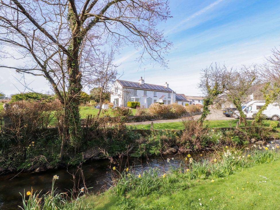 A house with trees and a stream in the garden at Ty Crigyll, Caergeiliog