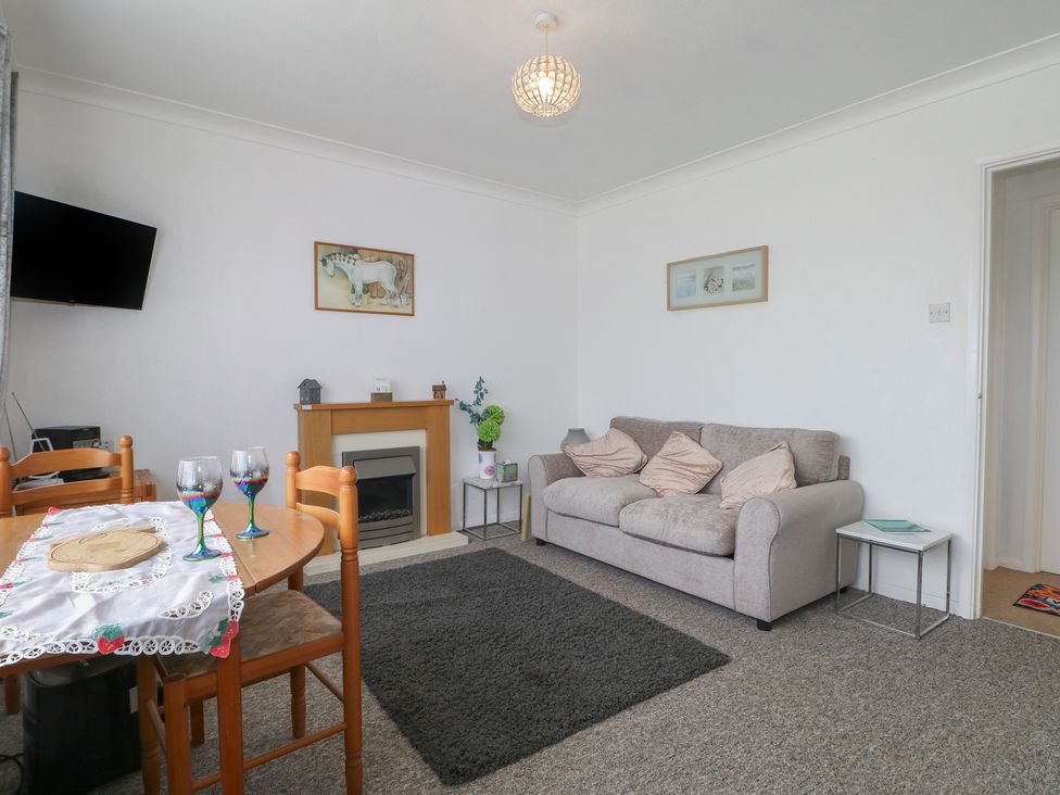 A living room with a sofa and dining area at 90 Bay View in New Romney