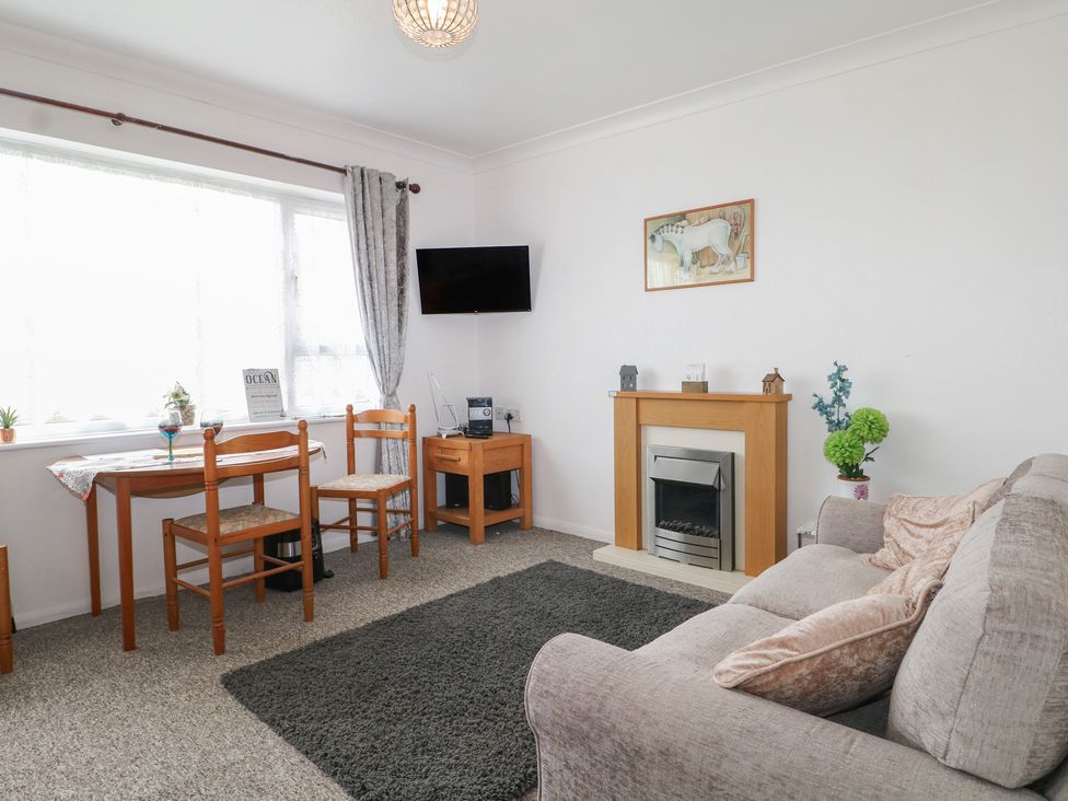 A living room with a sofa and fireplace at 90 Bay View in New Romney