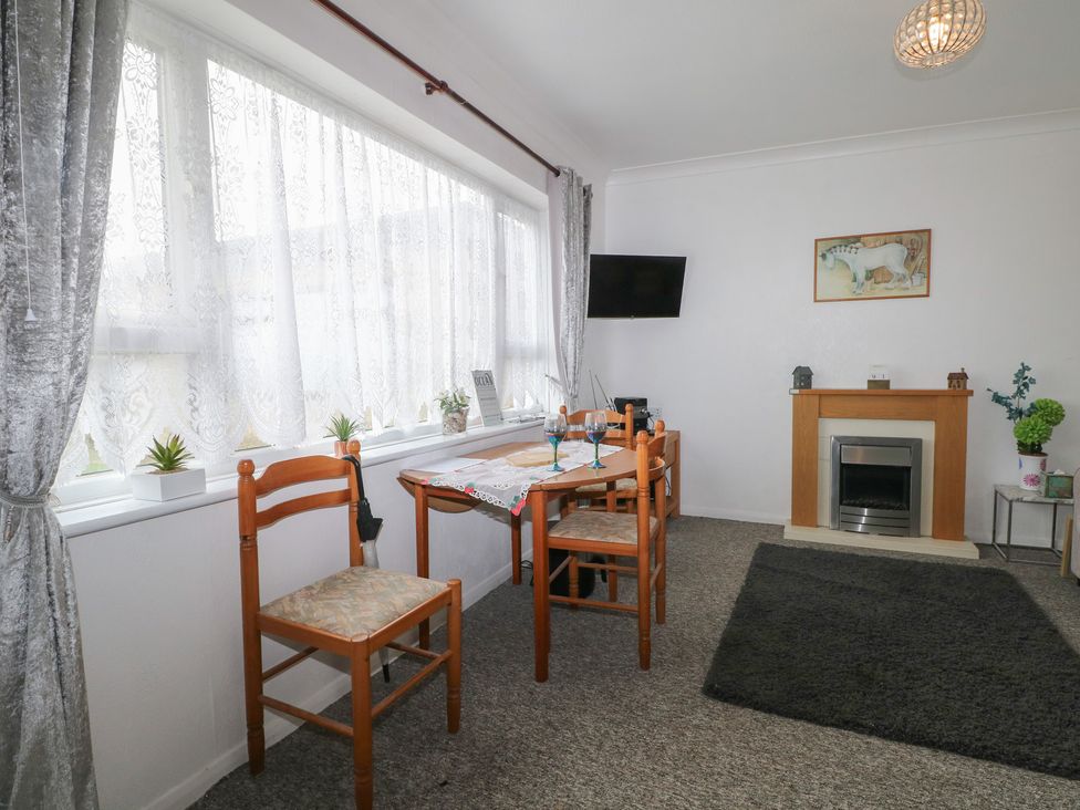 A living room with a table and chairs at 90 Bay View in New Romney
