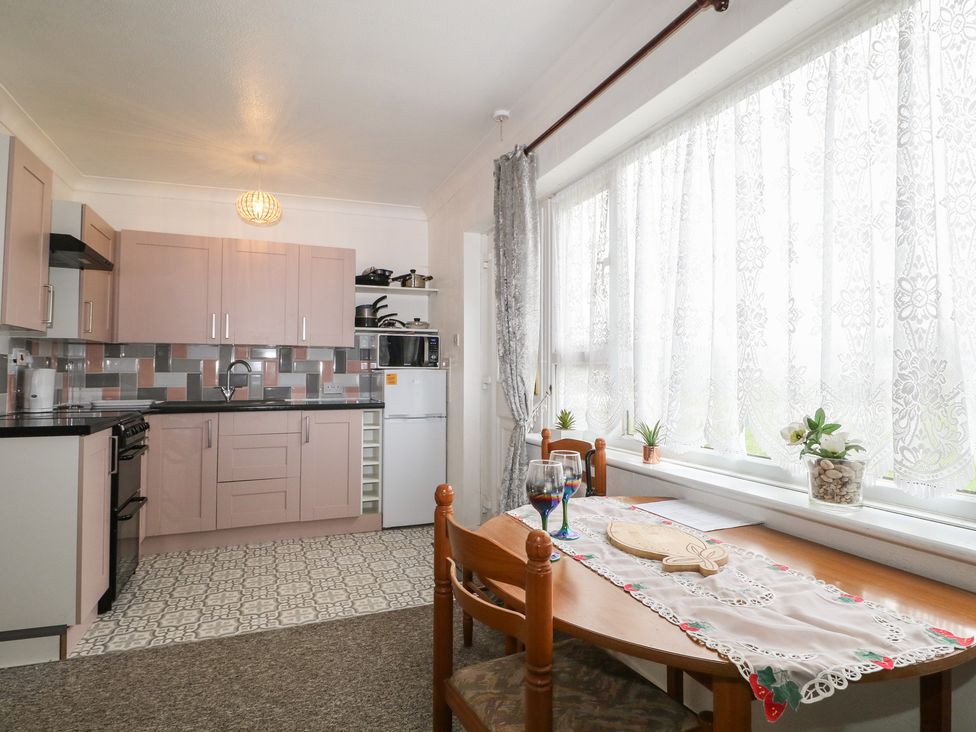 A kitchen with cabinets and a dining table at 90 Bay View in New Romney