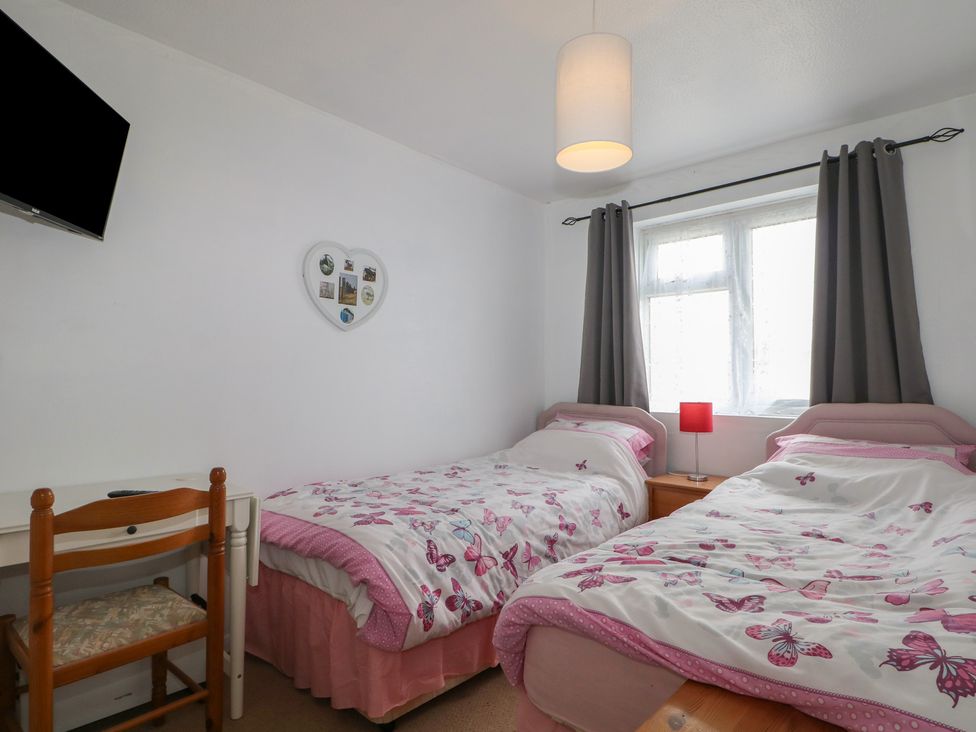 A bedroom with two beds and a desk at 90 Bay View in New Romney