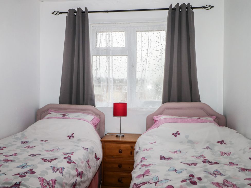 A bedroom with two beds and a window at 90 Bay View, New Romney