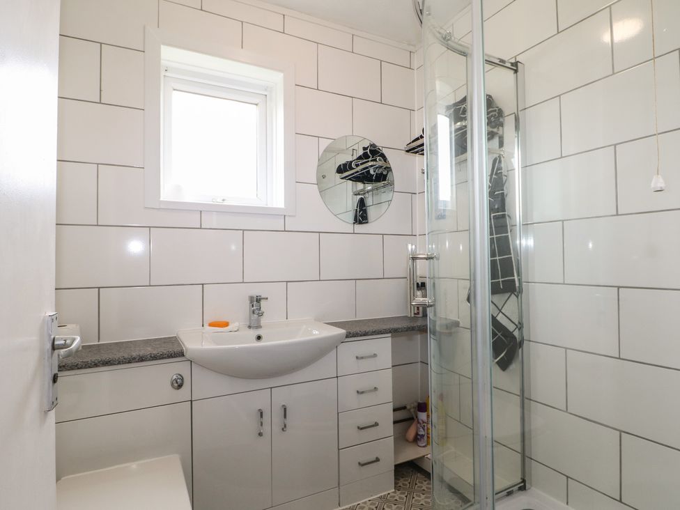 A bathroom with a shower and a wash basin at 90 Bay View in New Romney
