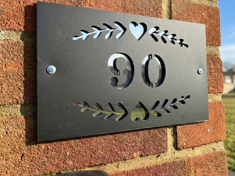 A house number plaque with the number 90 on a brick wall at 90 Bay View in New Romney